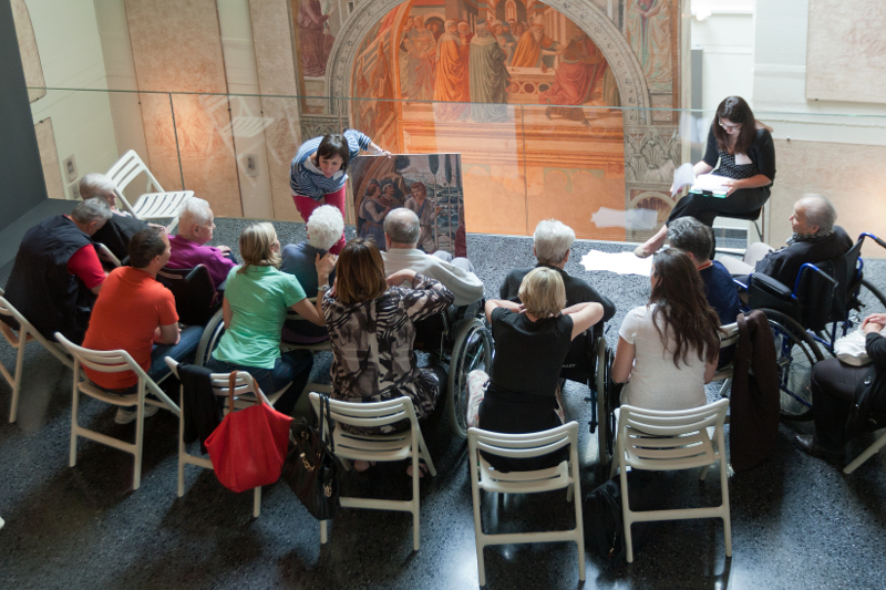 persone anziane e accompagnatori parlano durante una attività al museo
