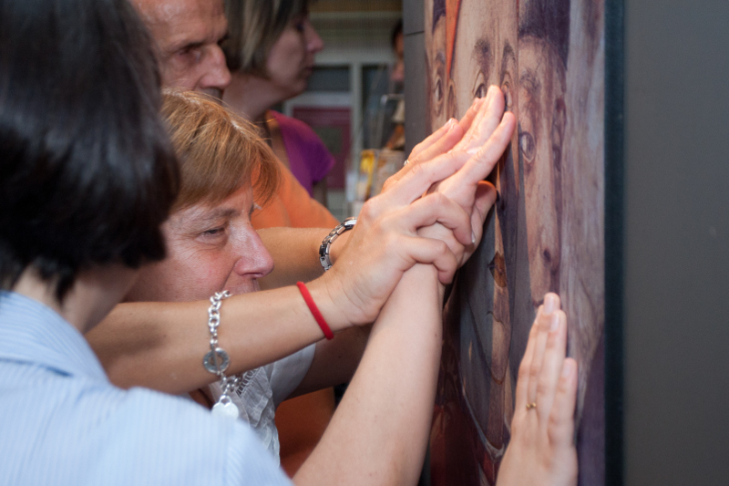 persona non vedente tocca i pannelli tattili del museo