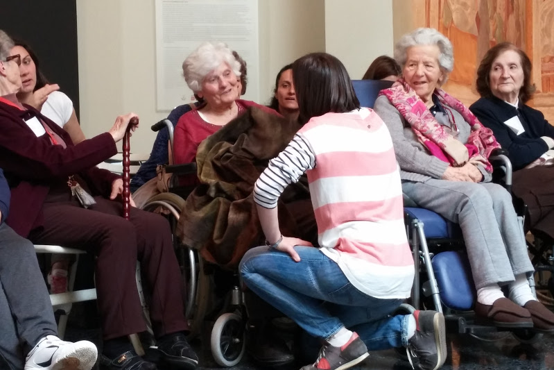 una educatrice del museo parla con le persone anziane durante una attività