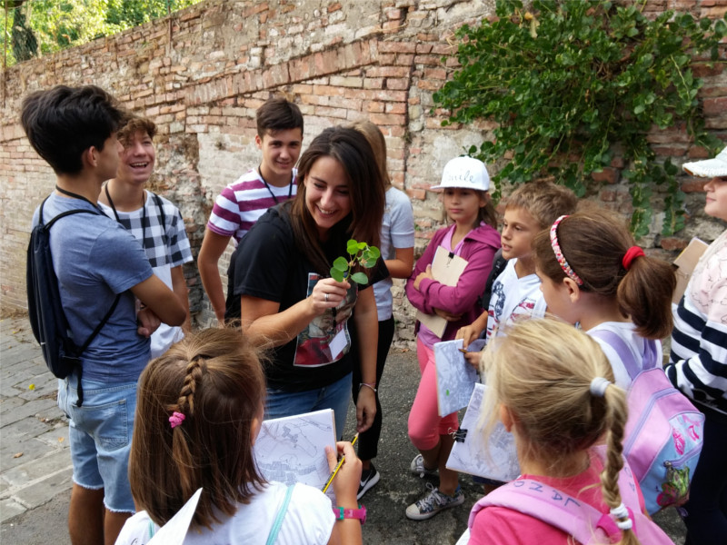 educatrice e ragazzi dell'alternanza sorridono insieme ai bambini 