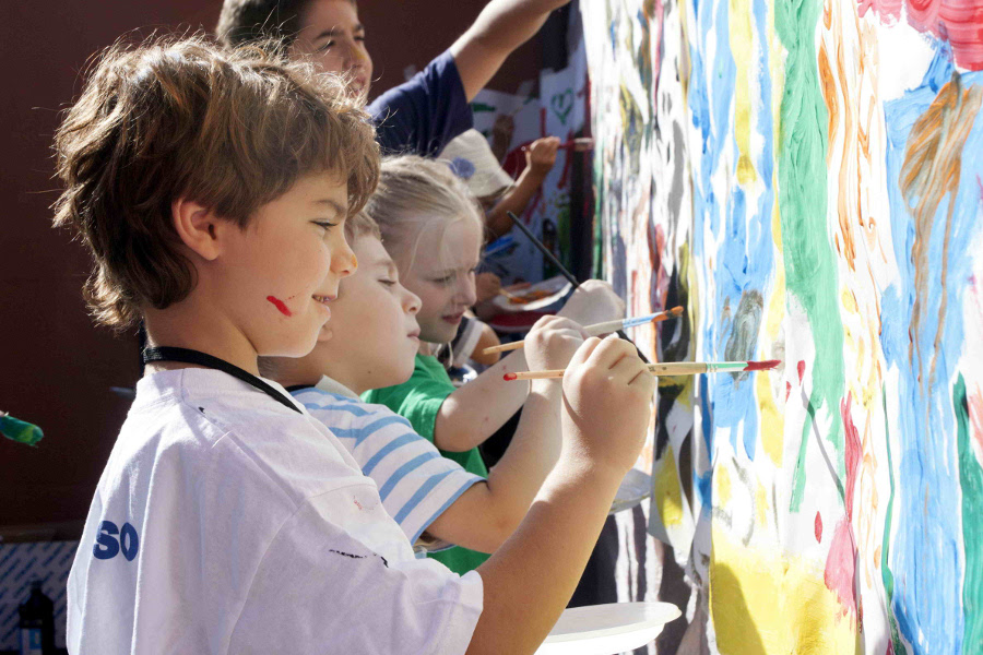 bambini dipingono all'esterno con le tempere su un cartellone